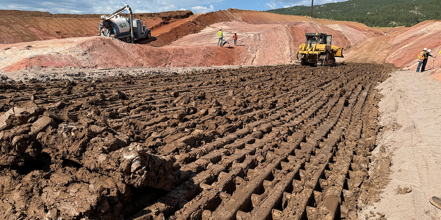 The clay core of the saddle dam with equipment in the background.