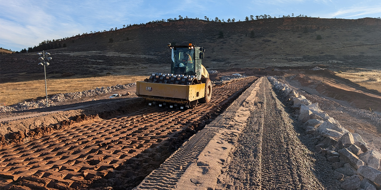 Heavy equipment compacts clay on the saddle dam. 